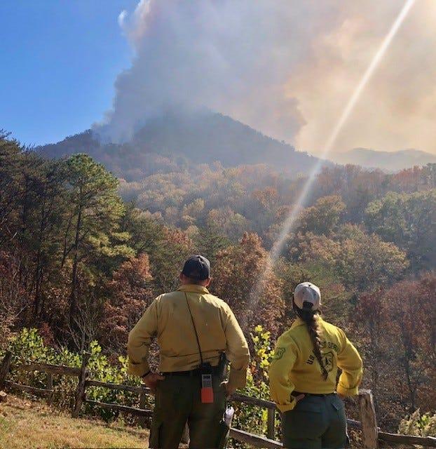 Two crew members stand looking at smoke coming from a wildfire in Nantahala National Forest