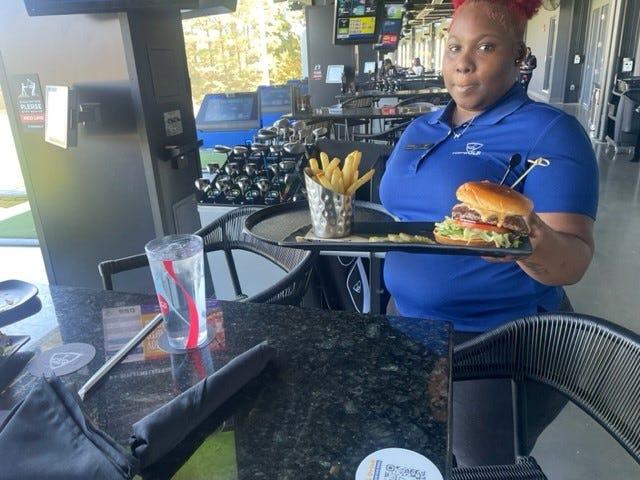 A Topgolf Memphis employee serves up the smokehouse burger and fries.