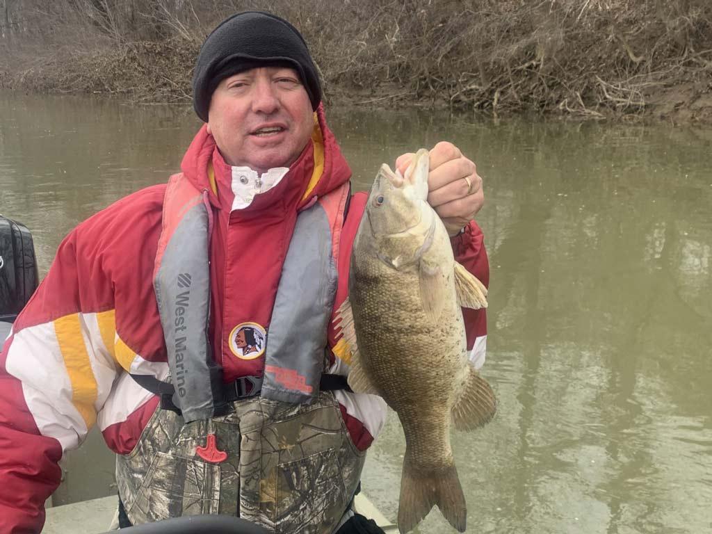An angler posing with a big Smallmouth Bass reeled in on the Susquehanna River.