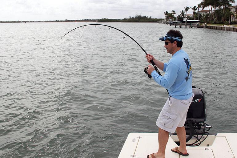 man with goatee and hat holding large snook close to camera with a topwater lure in mouth