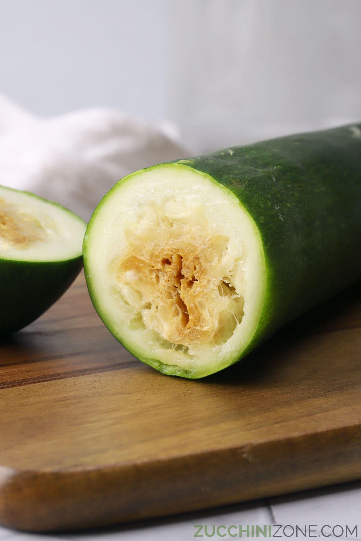 A rotten zucchini sliced in half to show discolored and shriveled flesh.