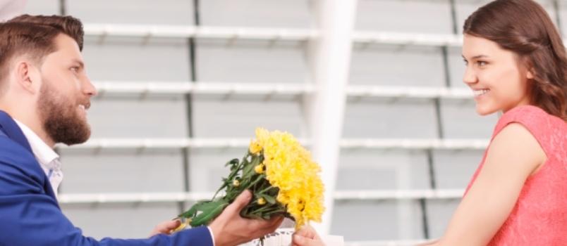 man giving yellow flowers to woman
