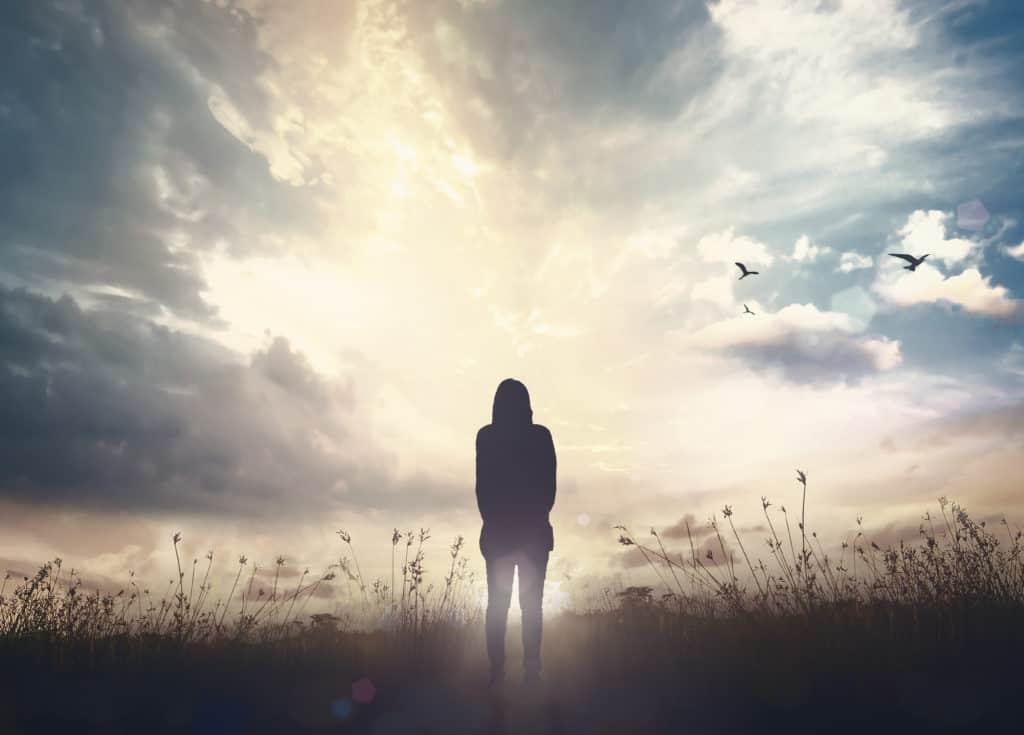 Silhouette of woman over autumn sunset meadow