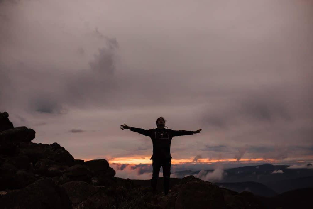 A person standing on a mountain with their arms outstretched.