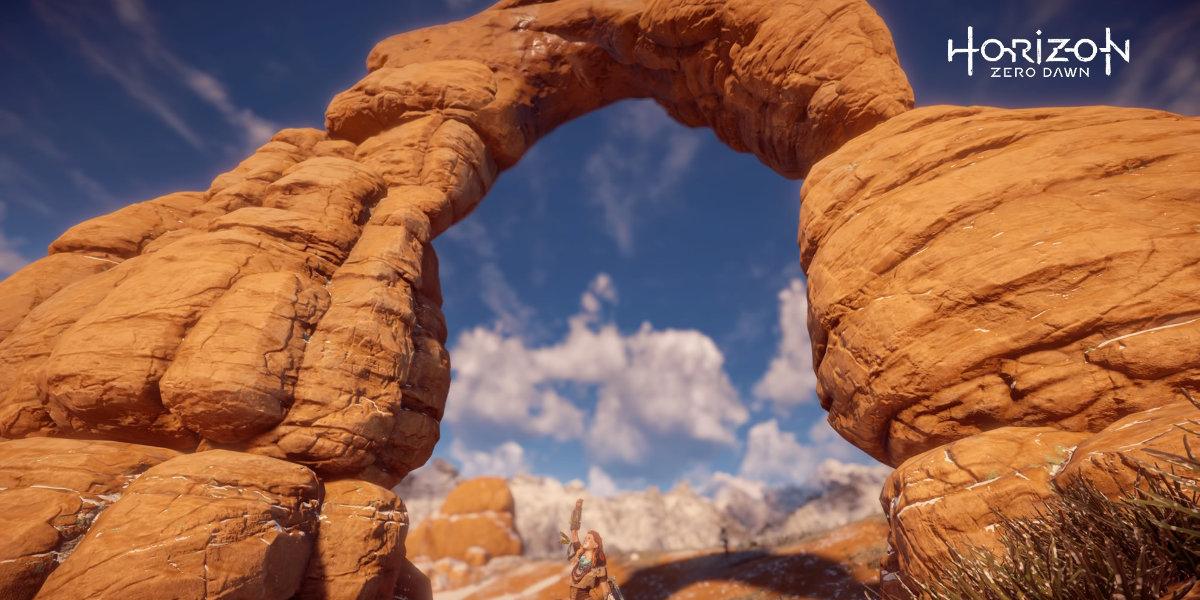 A video game screenshot of character standing underneath a large stone arch.