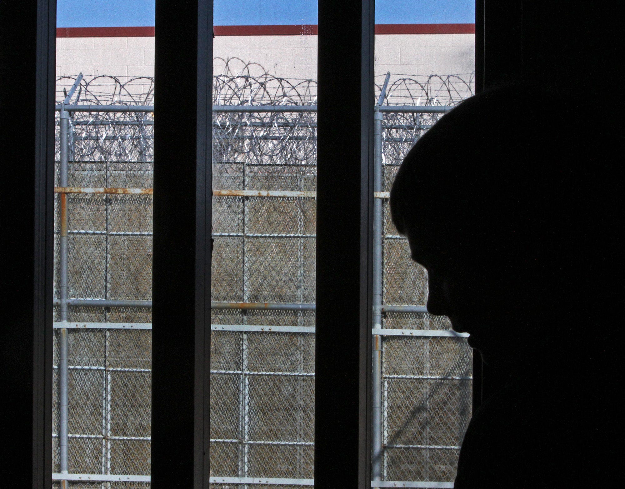 Gingerich is silhouetted in his cell, razor wire seen outside, as he spends his 14th birthday in jail on Feb. 17, 2012.