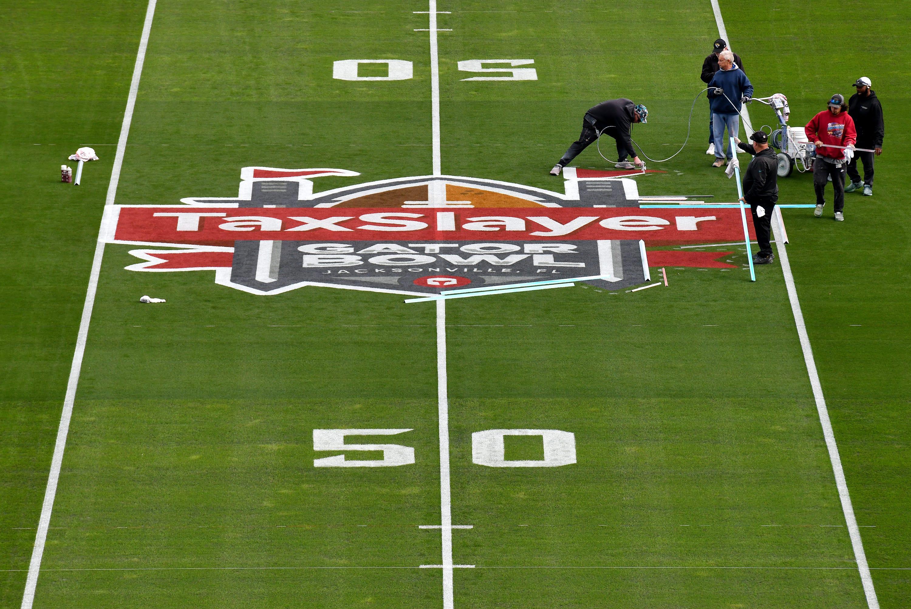 The turf crew at EverBank Stadium put the final touches on the TaxSlayer Gator Bowl logo at midfield Thursday, the day before the University of Kentucky takes on the Clemson Tigers.