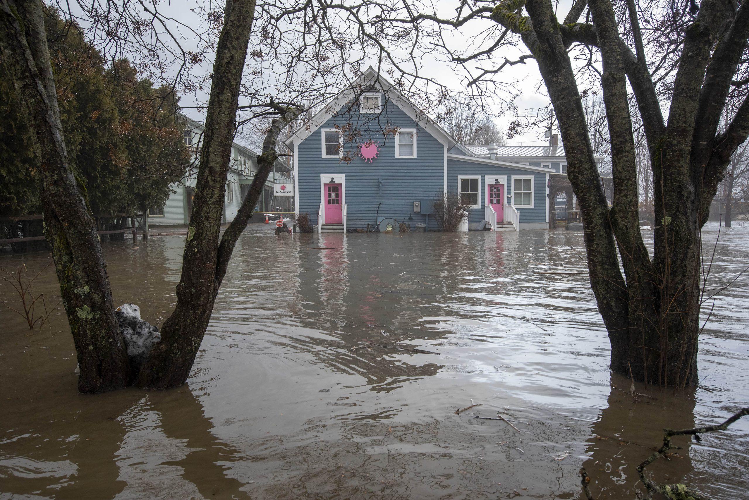 Floodwaters rage next to a road on a rainy day.