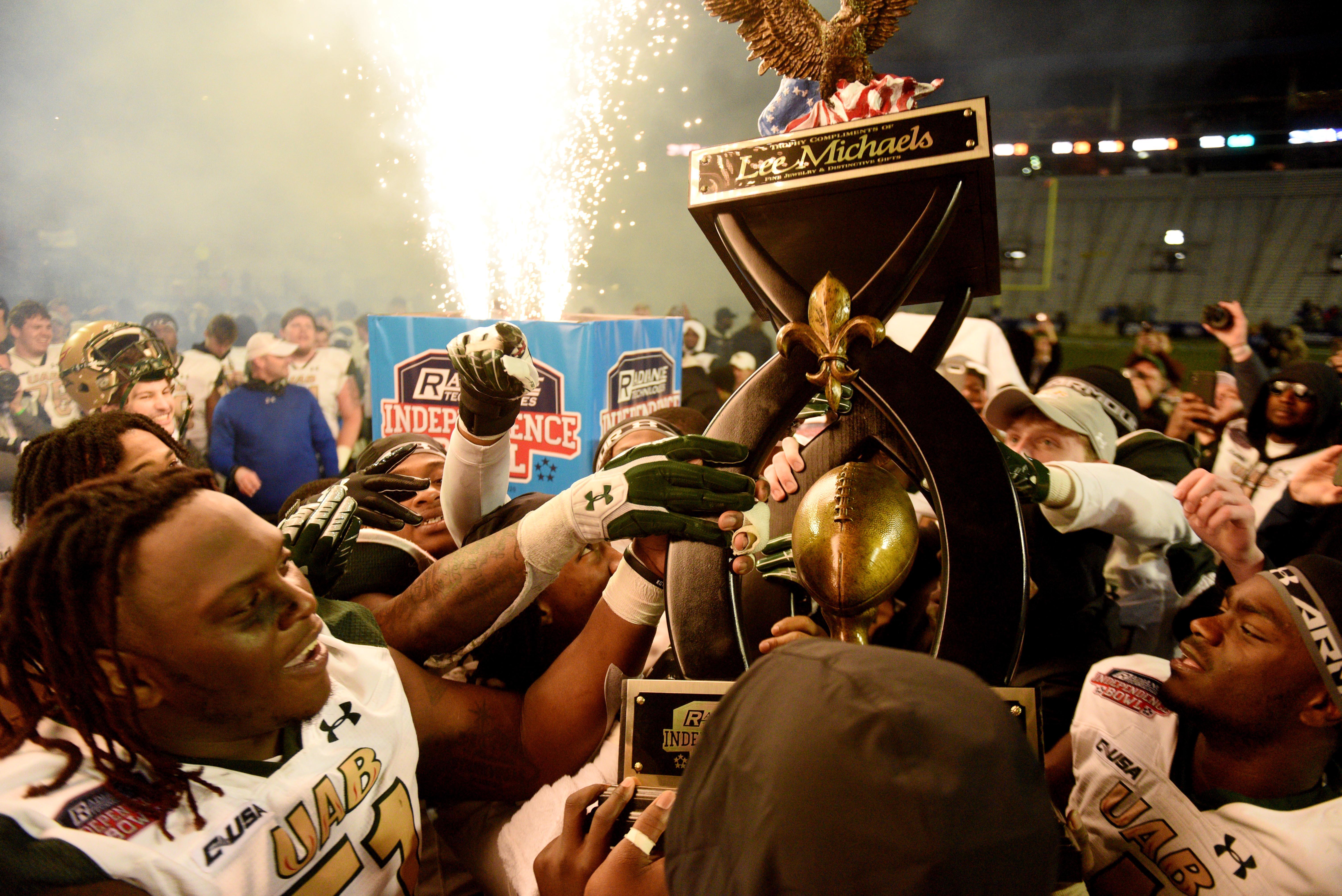 UAB players host their trophy after defeating No 13 BYU in the 2021 Radiance Technologies Independence Bowl in Shreveport.