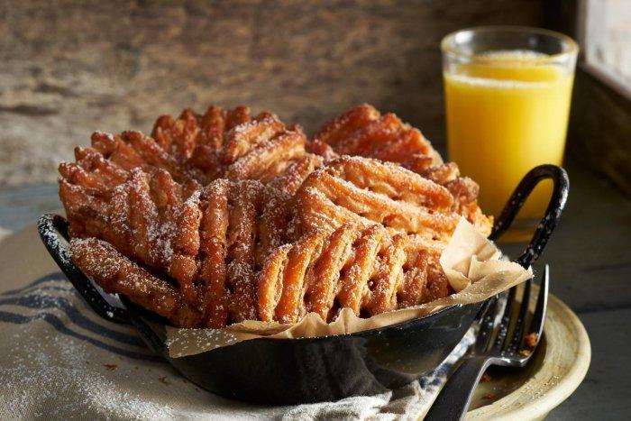 Sweet potato waffle fries with powdered sugar and a glass of orange juice