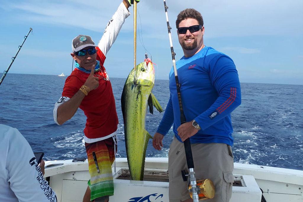 Two anglers pose either side of a Mahi Mahi caught in Aruba