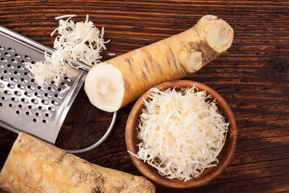 Fresh grated Horseradish roots on wooden table