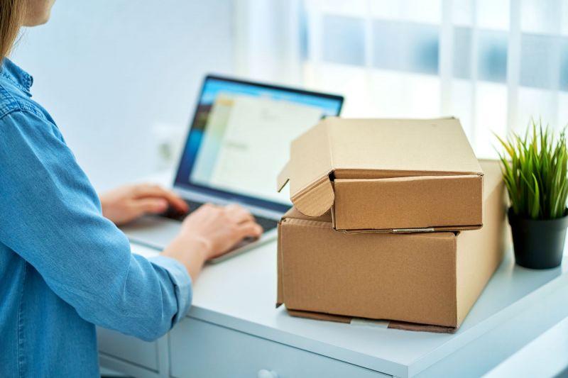 Woman on laptop next to pile of parcels