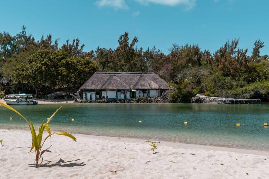 white-sand beach and turquoise ocean with a small wooden hut in the background - Mauritius Ile aux Cerfs tour