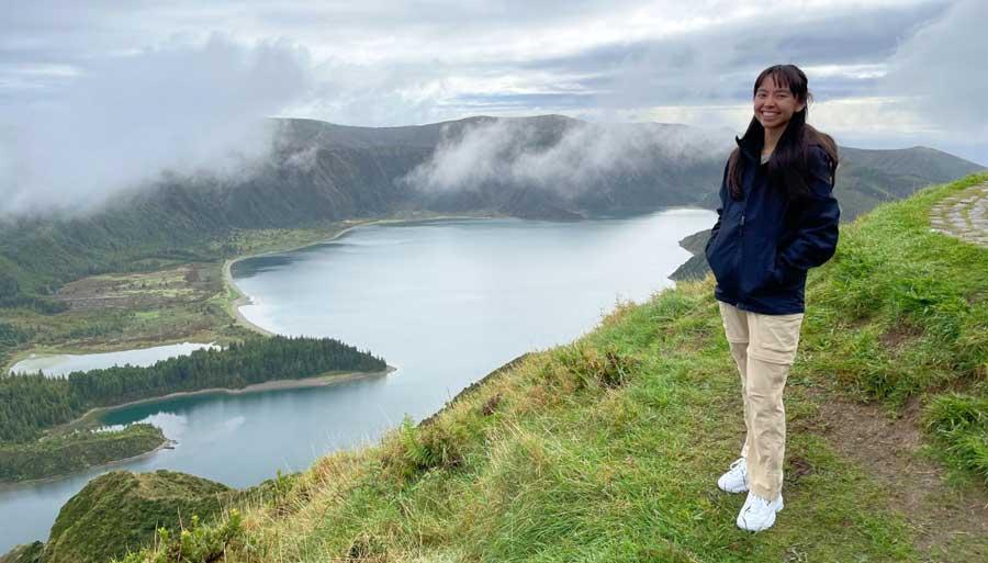 The author smiling for a photo with a view on her bcaground