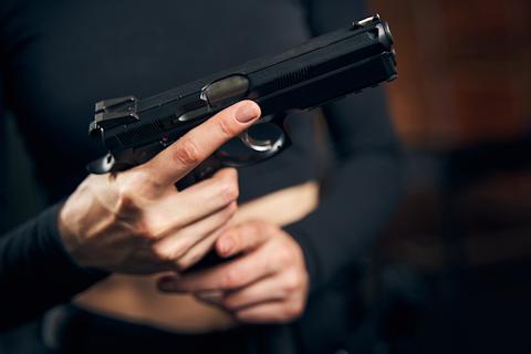 A person wearing black and holding her gun with her finger off the trigger