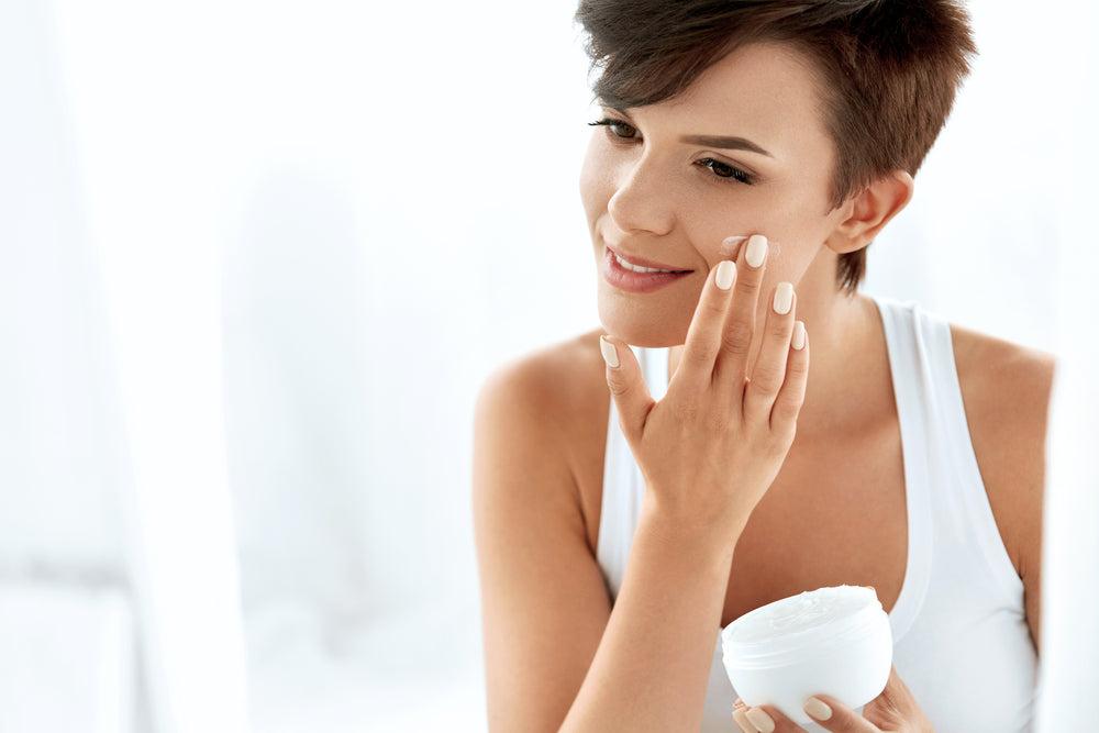 Woman applying moisturizer to her face