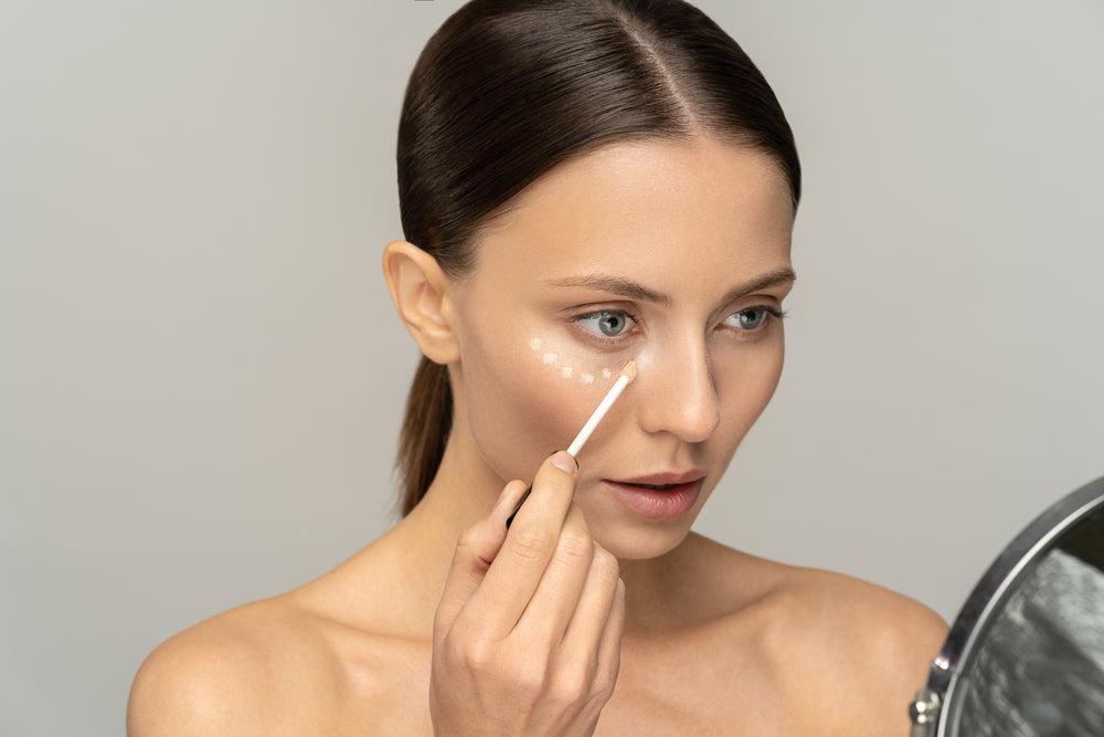 Woman putting dots of concealer under her eyes as part of her makeup routine