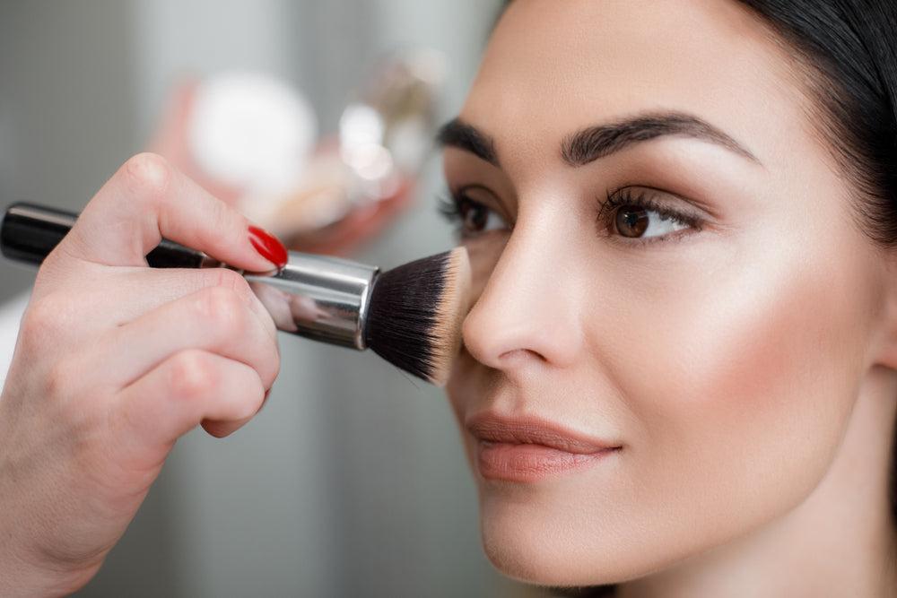 Woman putting blush makeup on her cheeks