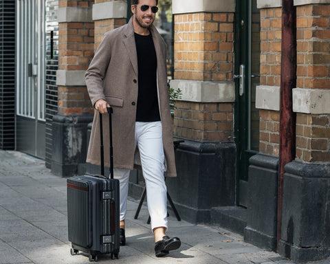 Stylish man walking with a polycarbonate carry-on suitcase