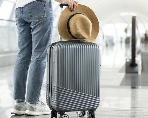 Man standing beside an ABS suitcase in an airport