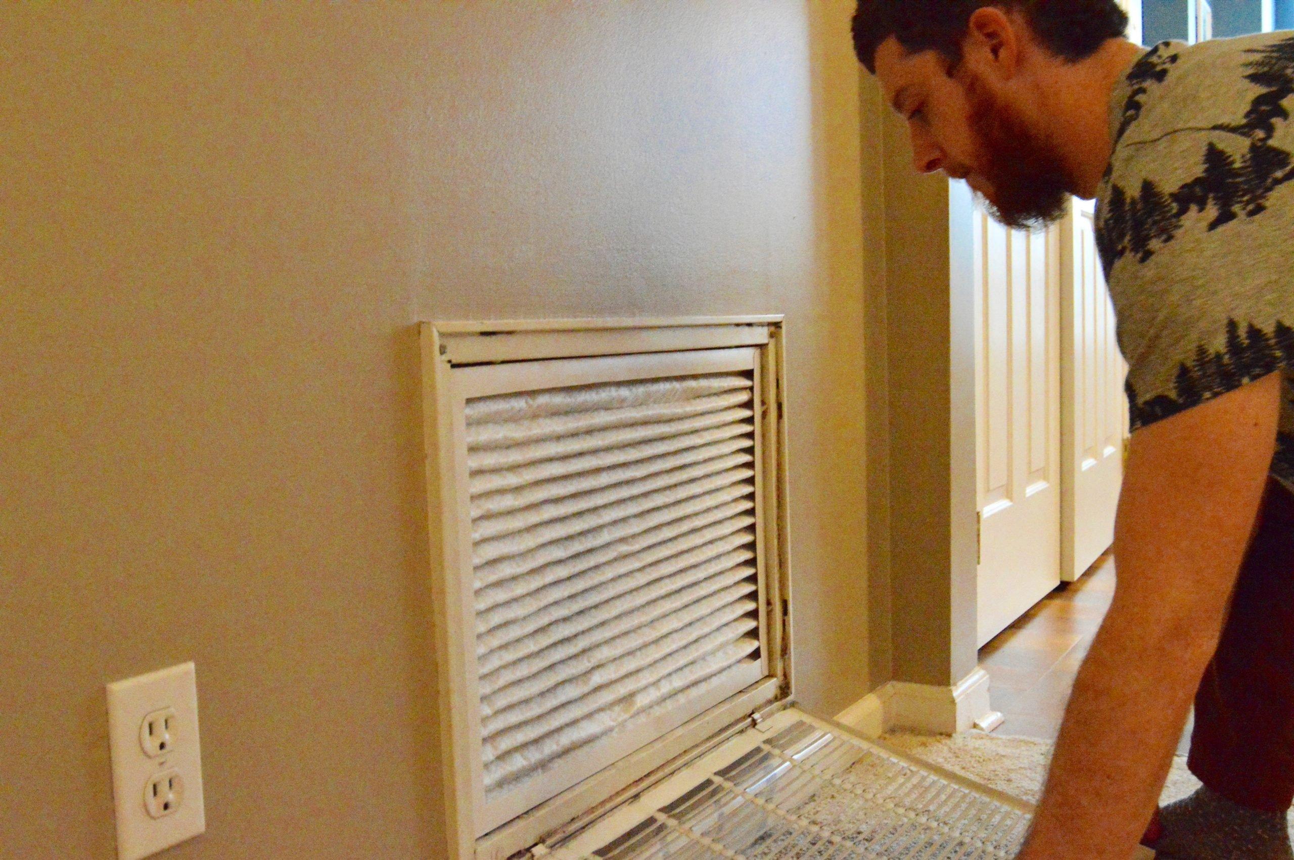 man changing HVAC filter in wall