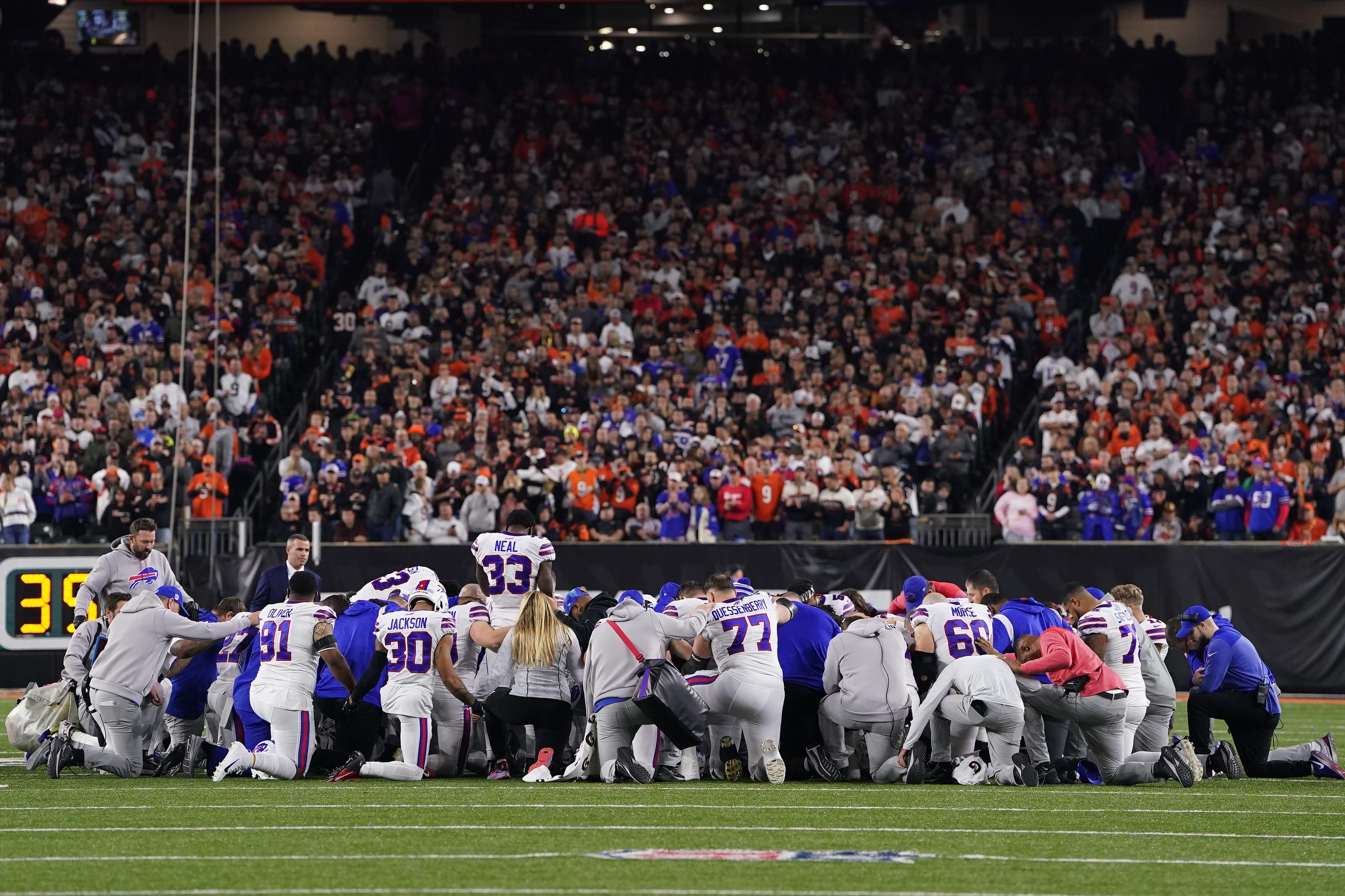 Bills players huddle and pray after teammate Damar Hamlin after he collapsed on the field in Cincinnati on Monday night.