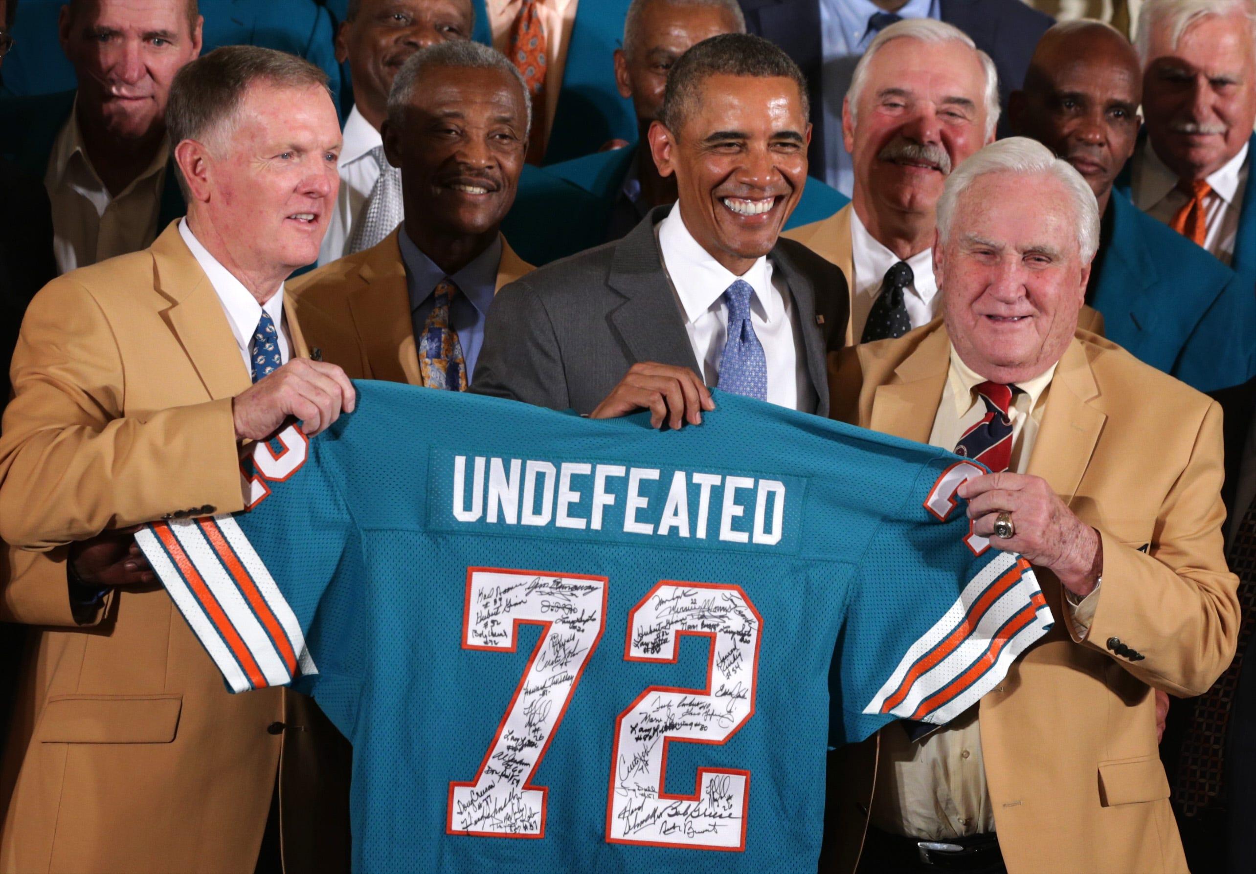President Barack Obama poses for photos with members of the 1972 Miami Dolphins including head coach Don Shula (R), quarterback Bob Griese (L), and running back Larry Csonka (4th L) during an East Room event August 20, 2013 at the White House in Washington, DC. President Obama hosted the undefeated 1972 Super Bowl champion who didn
