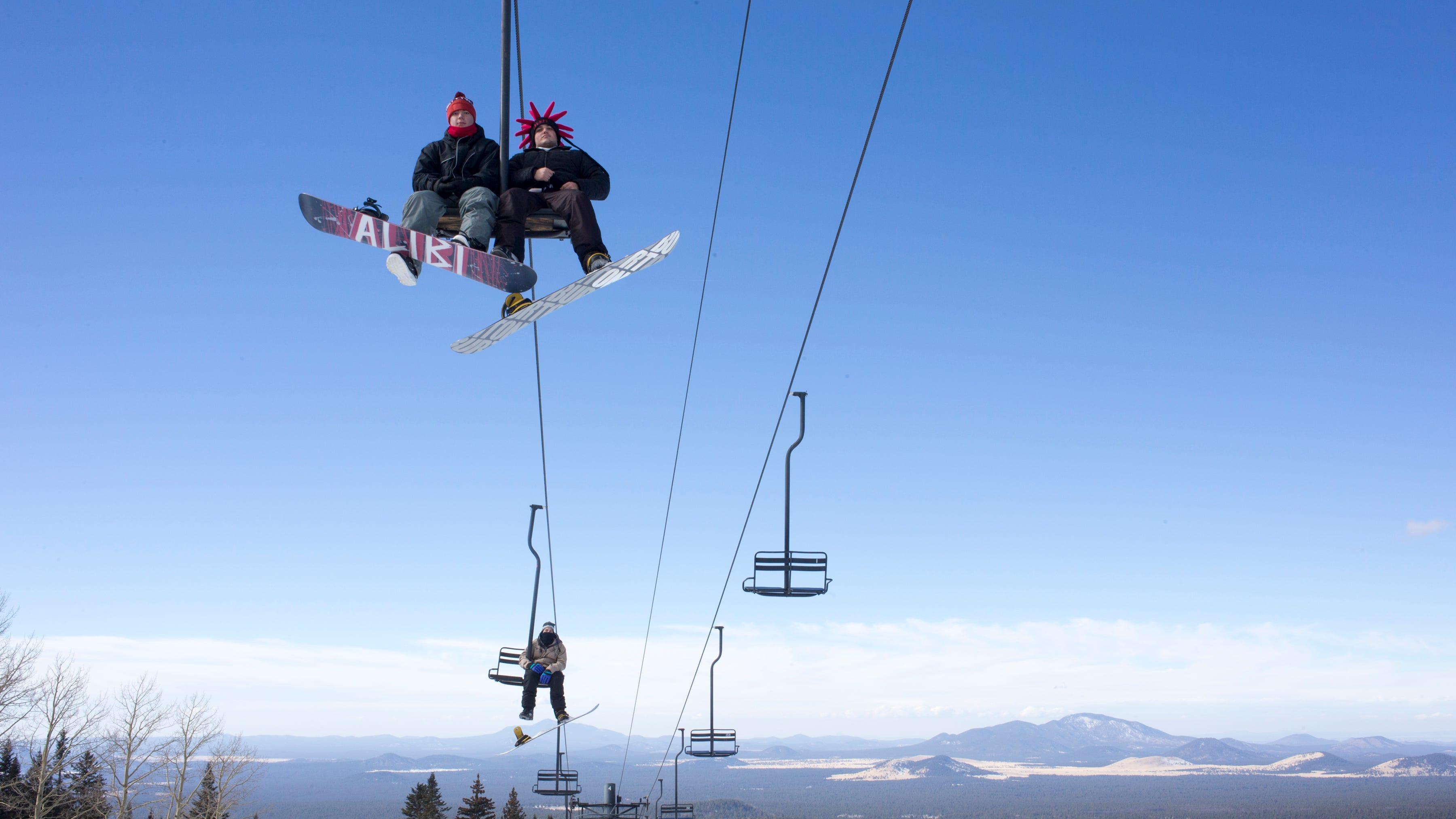 Snowboarders ride the ski lift at Snowbowl last December. The resort near Flagstaff has been acquired by an investor.