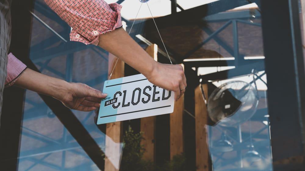 female turning sign from open to closed on the entrance door