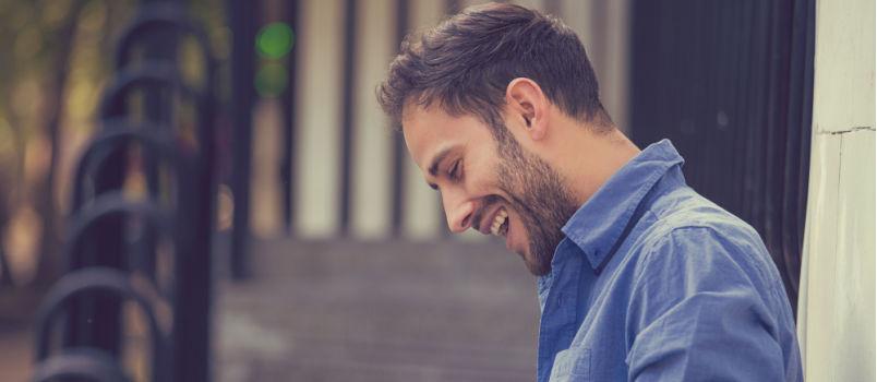 Man smiling while looking into his phone