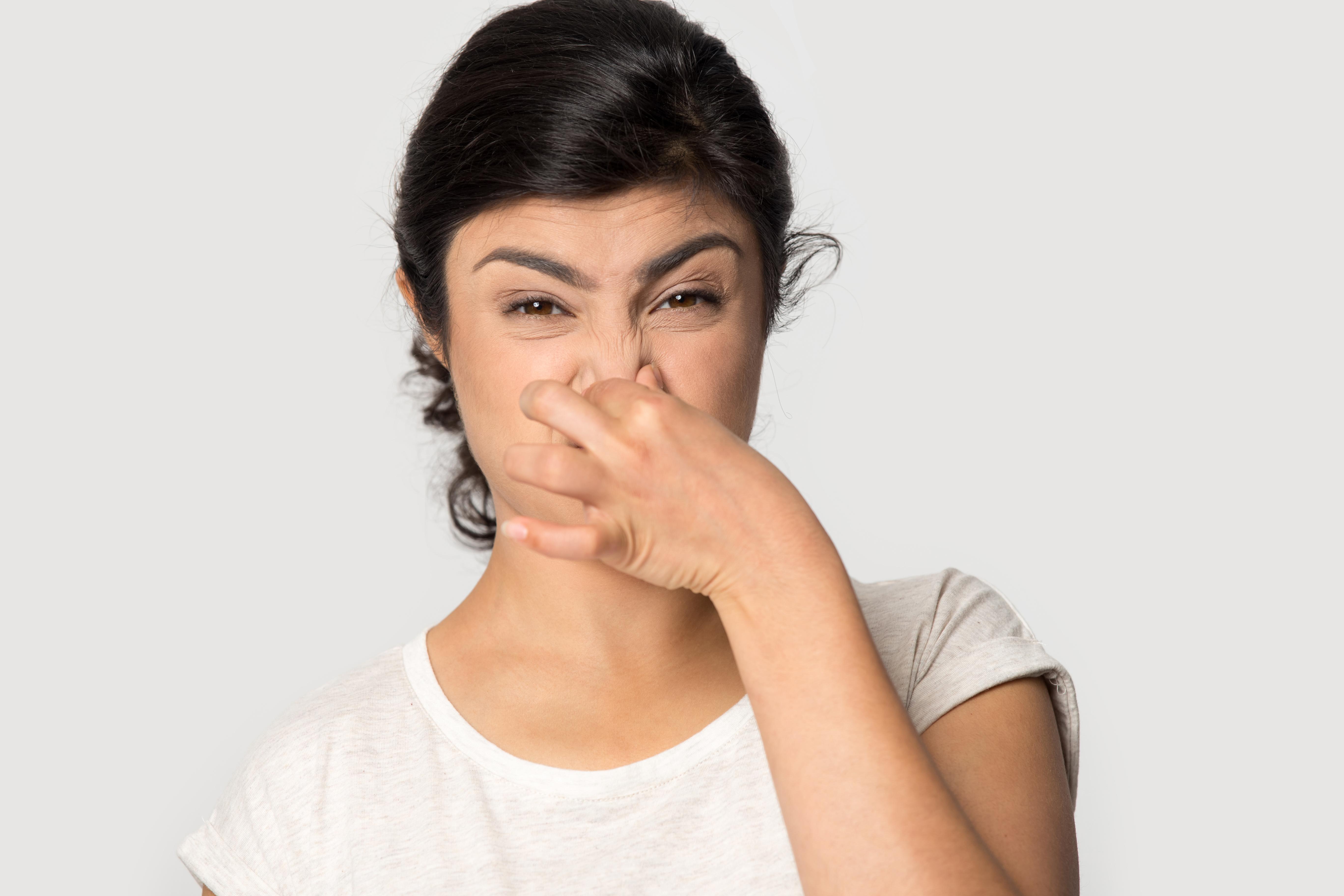 Woman smelling an unpleasant odor