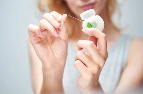 a woman holding dental floss in her hands