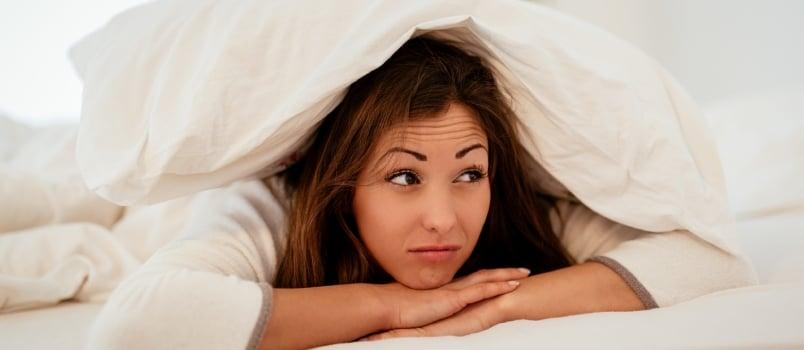 Alone girl on bed under blanket