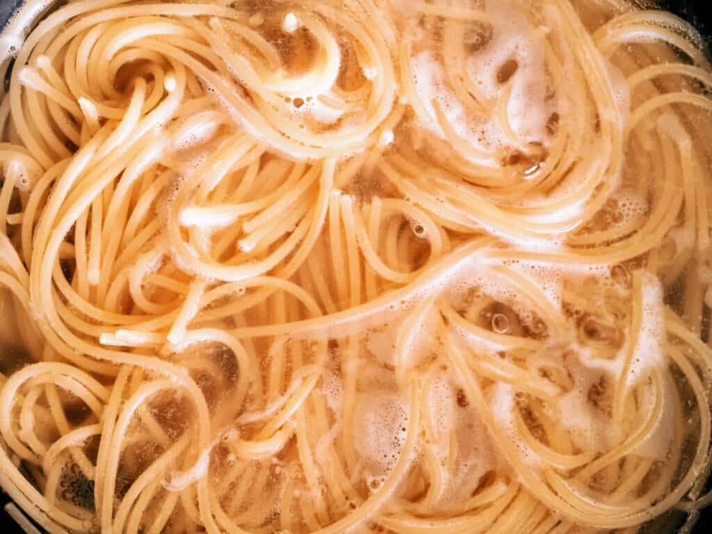 Close up of spaghetti boiling in a pot of water.