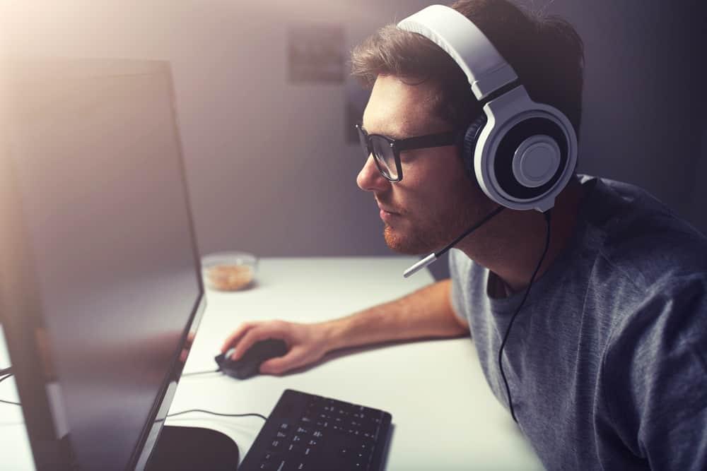 Man in headset playing computer video game at home