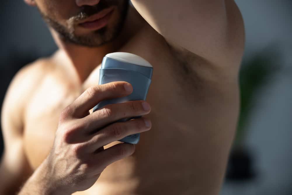 Close up shot of young handsome man with muscle body using deodorant
