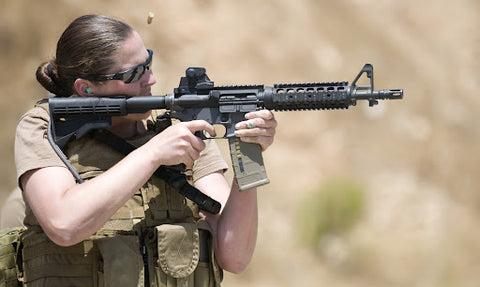 A lady holding a rifle out in the open