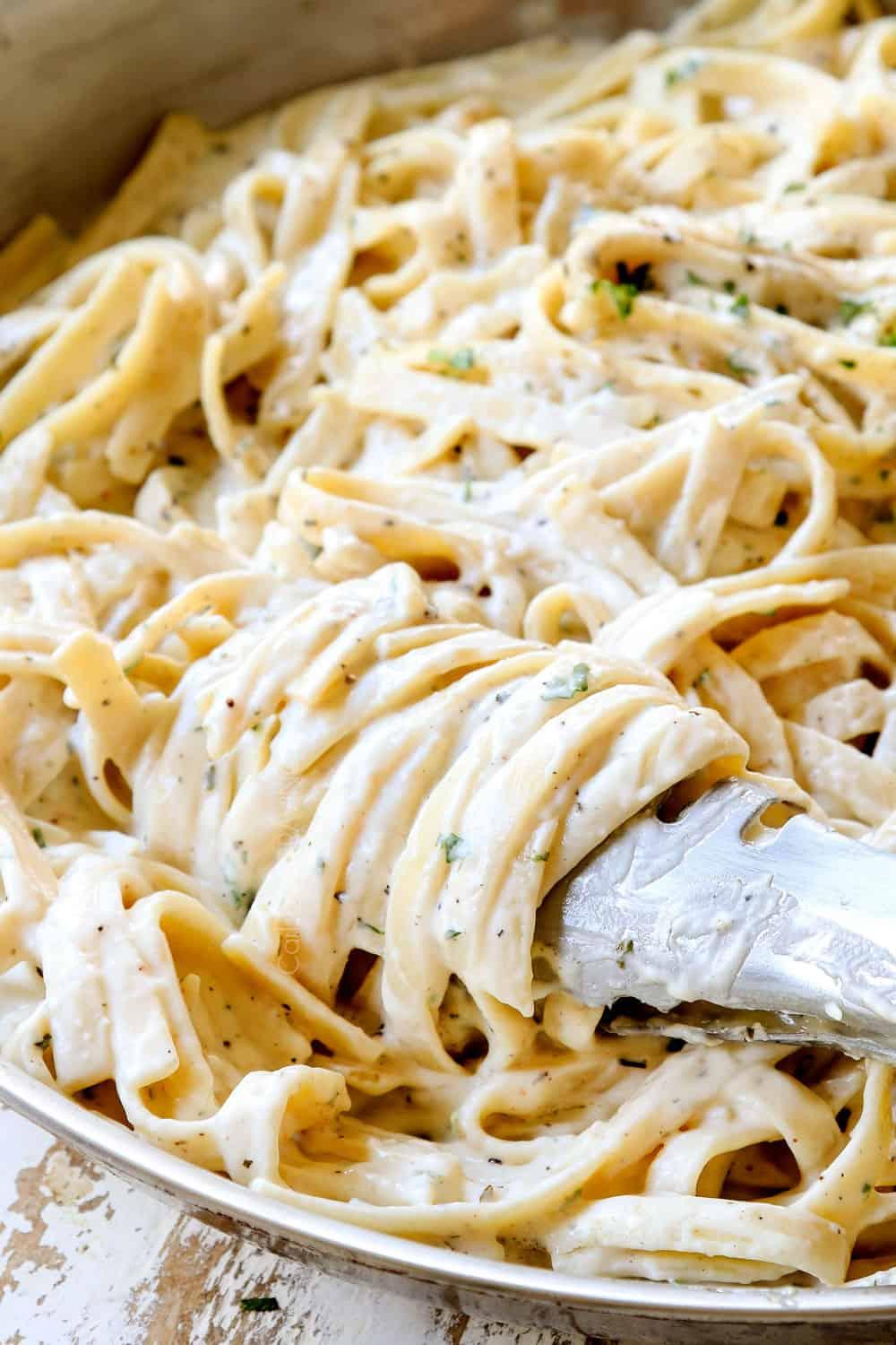 twirling tongs with best fettuccine Alfredo showing how creamy it is