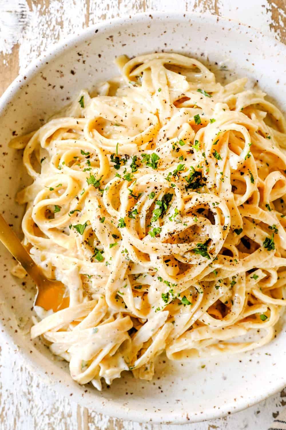 top view of fettuccine Alfredo in a bowl with freshly cracked pepper showing how creamy it is