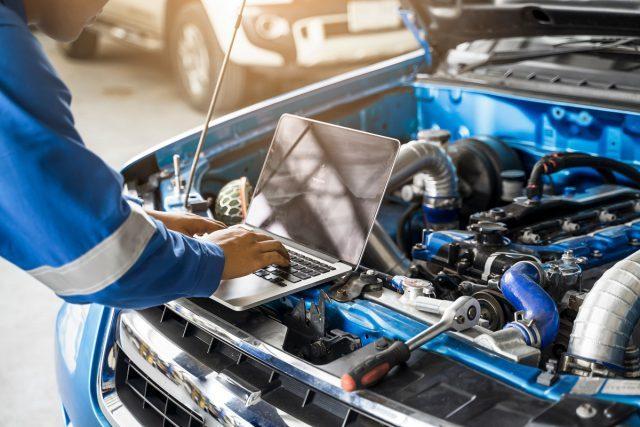 Mechanic Asian man close up using laptop computer examining tuni