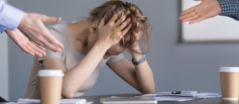 Stressed Young Businesswoman Holding Head In Hands Suffering From Unfair Gender Discrimination At Work Concept, Female Employee Frustrated By Male Colleagues Bullying Humiliating Woman At Workplace