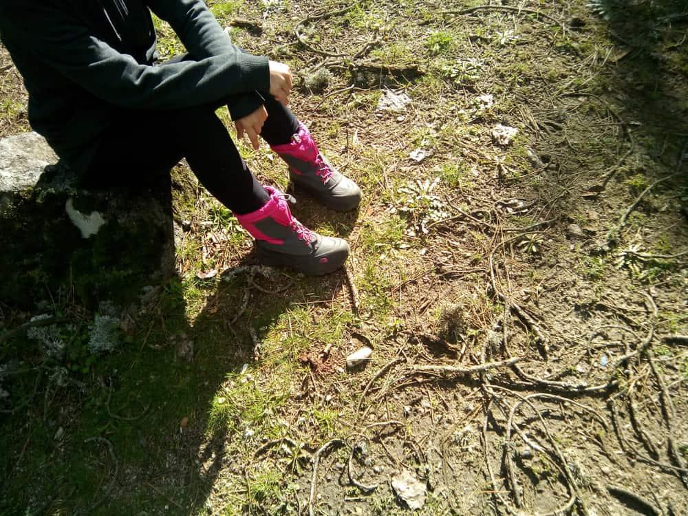 young woman wearing a pink a grey snow North Face boots during a hike