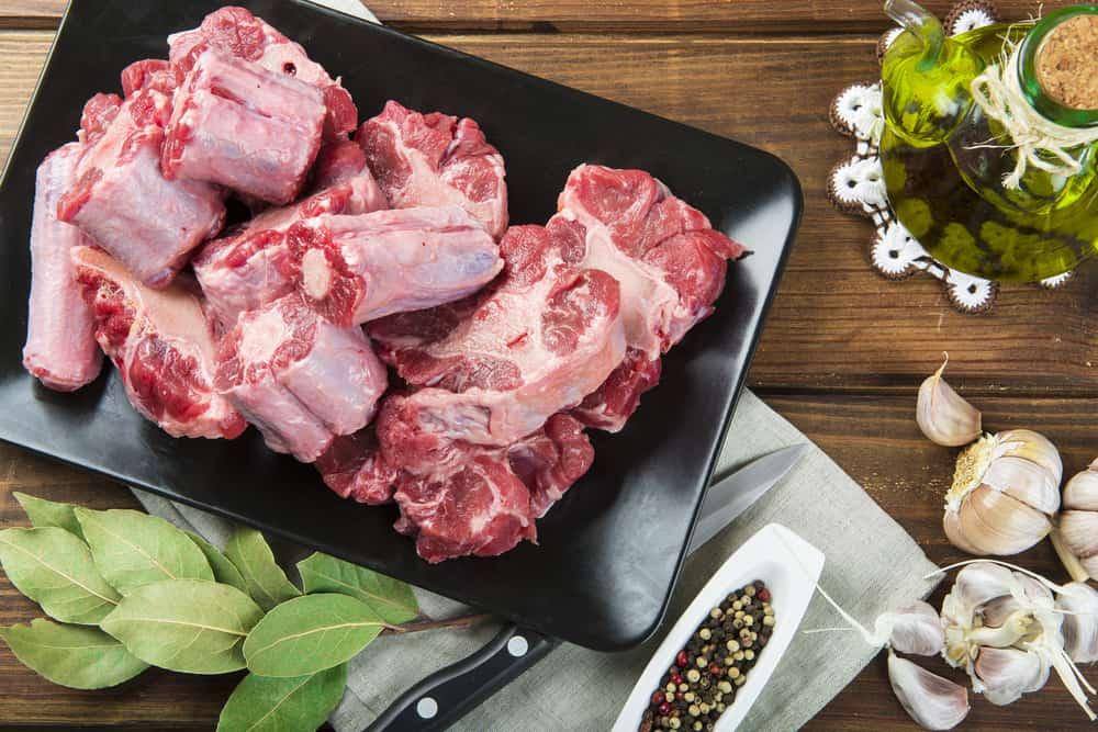 Raw oxtail cut on a tray with olive oil and spices to cook it on the table of the kitchen