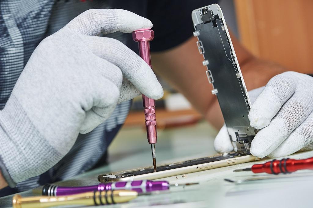 Repairman uses screwdriver on smartphone