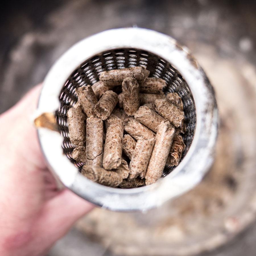 Amazen Tube smoker full of smoking pellets being placed inside a Big Green Egg.