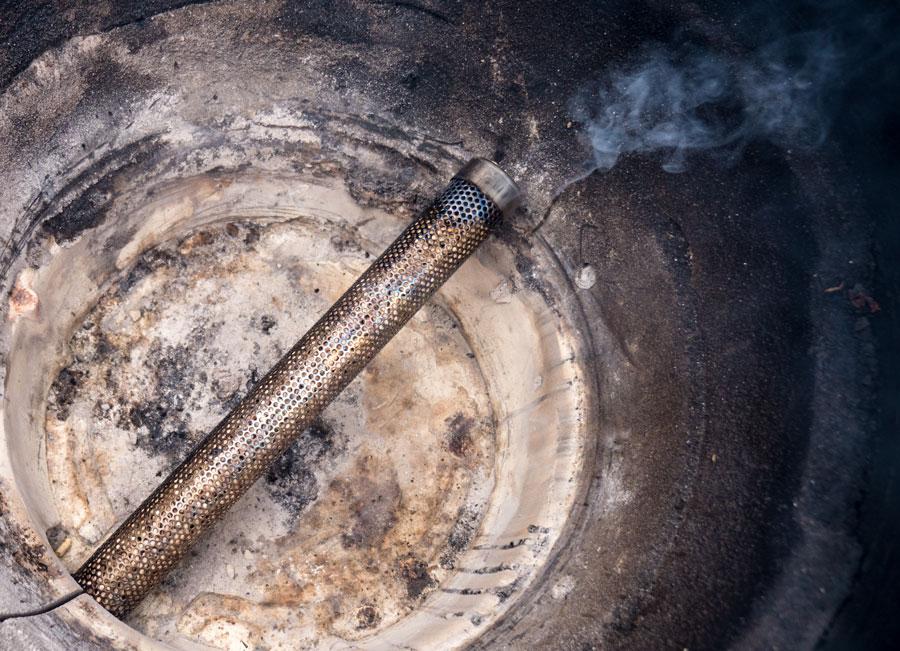 Amazen smoking tube emitting thin blue smoke inside a Big Green Egg.