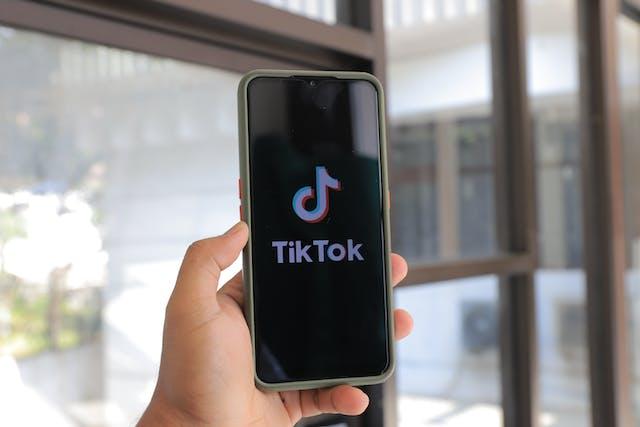 A person taps the TikTok app on their phone to launch it.