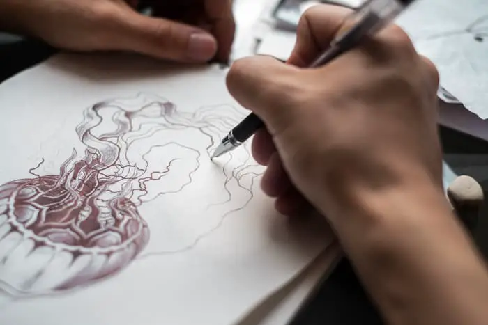A tattoo artist sketching an image of a jellyfish.