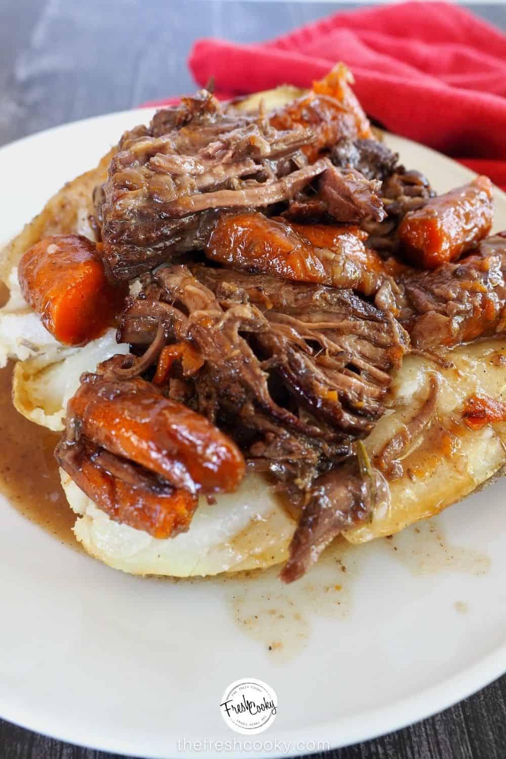 Steaming hunk of pot roast coming out of a red dutch oven on a wooden spoon